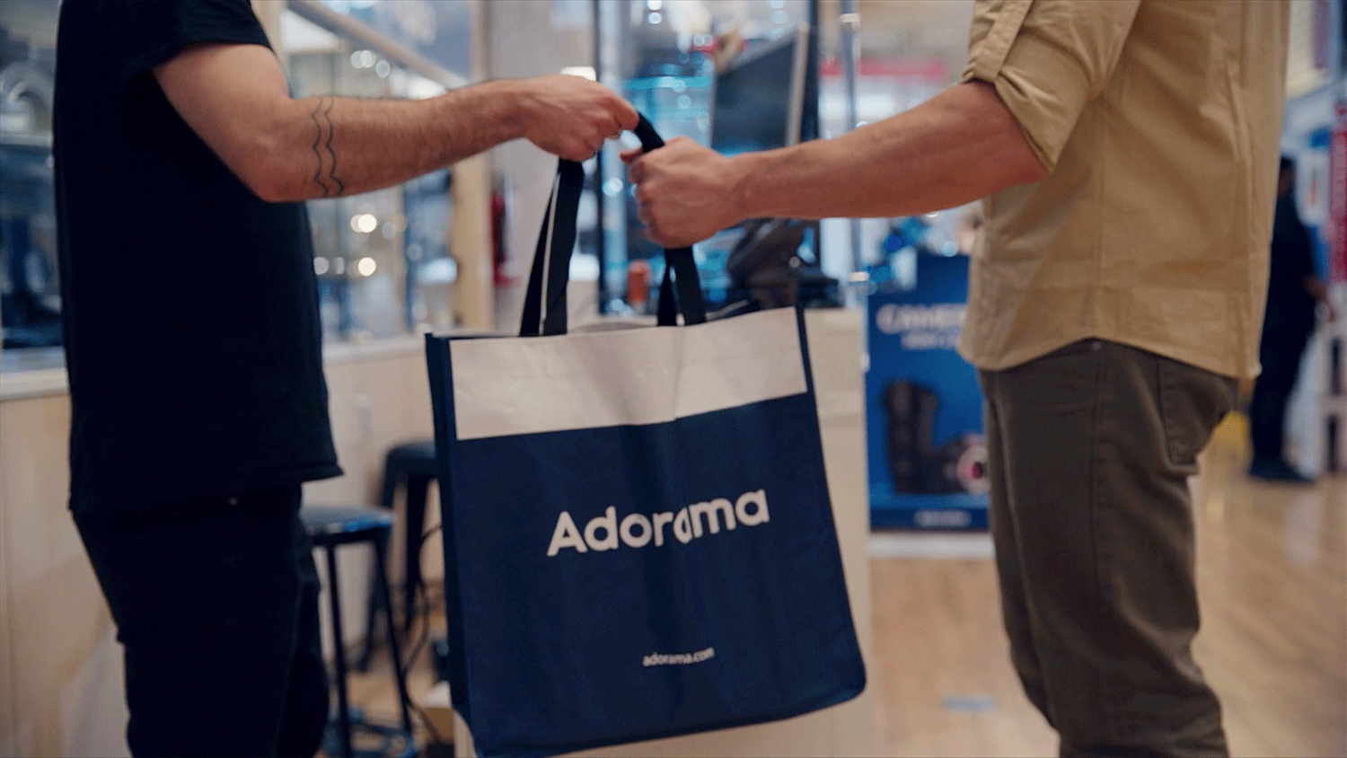 Sales person hand over Adorama bag of goods to customer